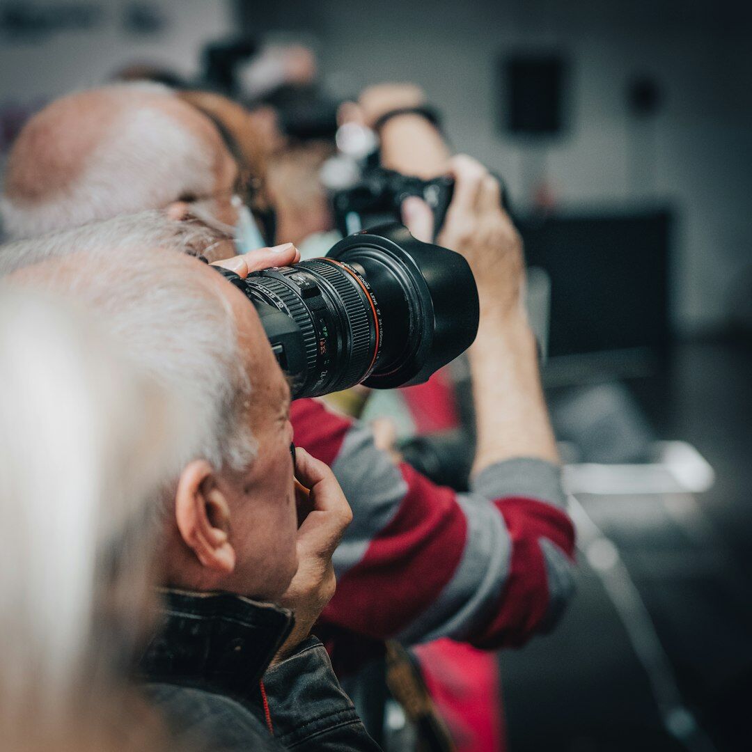 Audience watching a live streamed event with cameras in foreground